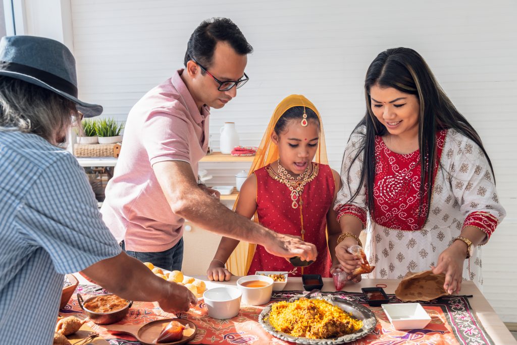 An Indian family standing in the kitchen preparing food