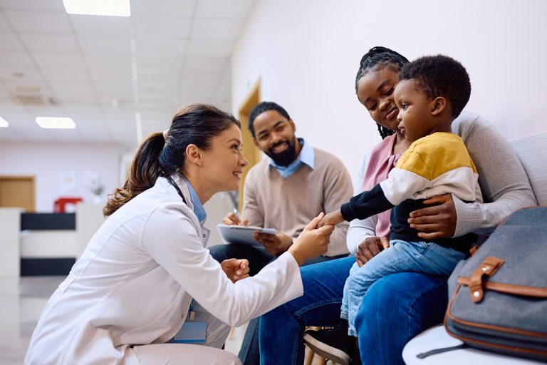 Doctor-holding-hand-on-African-American-boy-with-parents-in-medical-clinic